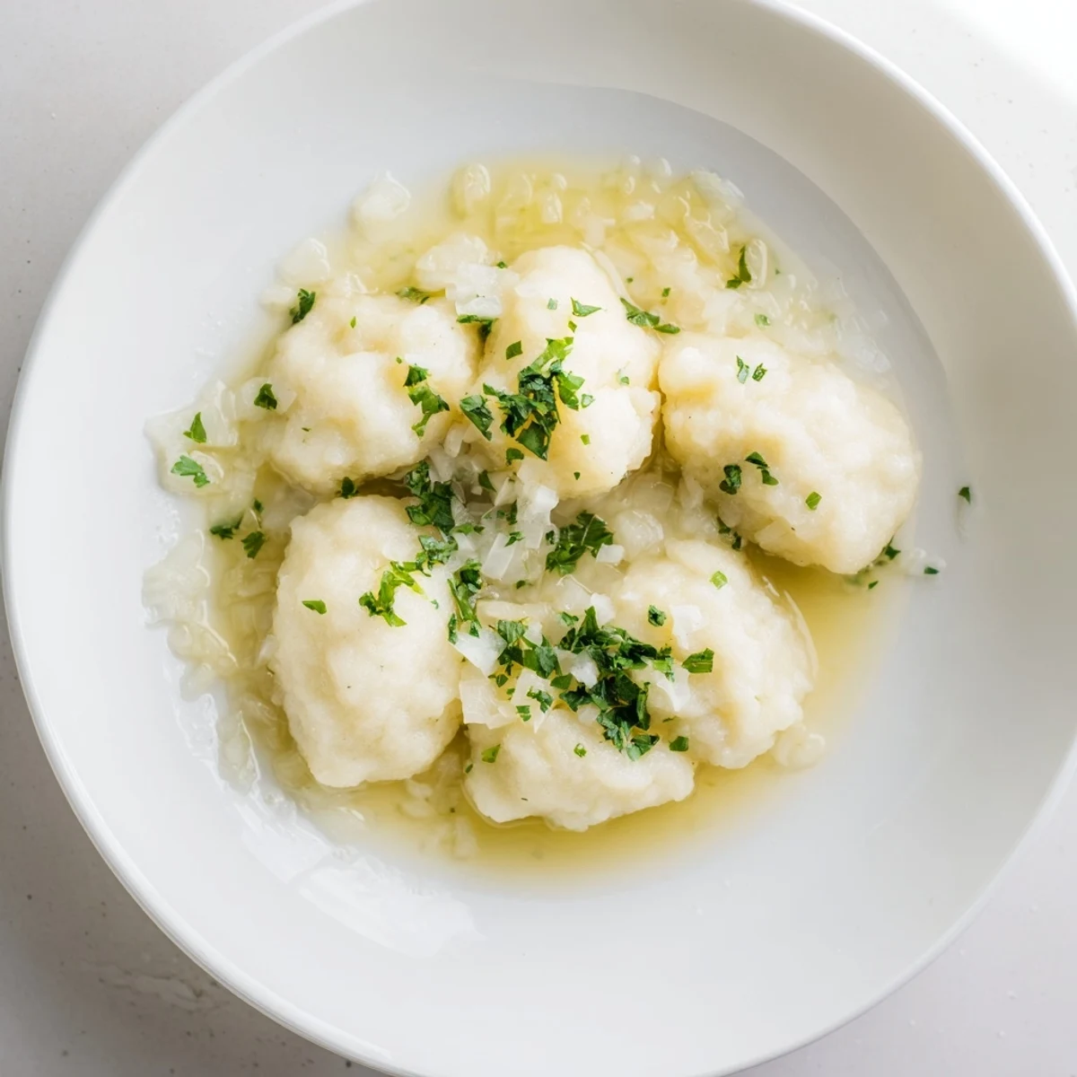 Close-up of fluffy Kartoffelklöße, drizzled with savory sauce, ready to be served with butter.
