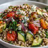 Vibrant Mediterranean Farro Pasta Bowl with colorful veggies, feta, and pine nuts served warm.