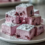 Klein geschnittene Black Currant Marshmallows ruhen auf Puderzucker und Maisstärke, eine glutenfreie Süßigkeit.