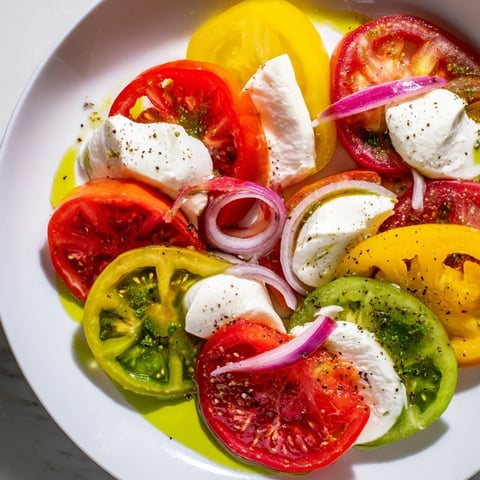 Summer Tomato Salad with Basil Oil and Fresh Mozzarella, a colorful, layered arrangement on a platter.