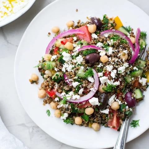 Ein farbenfroher griechischer Power-Salat aus Quinoa, Linsen, Kichererbsen und Gemüse in einer würzigen Vinaigrette.  