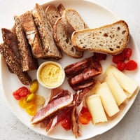 Alpine snack board Plancha Montagne Aventure collation, featuring cheeses, meats and fruit, ready to eat.